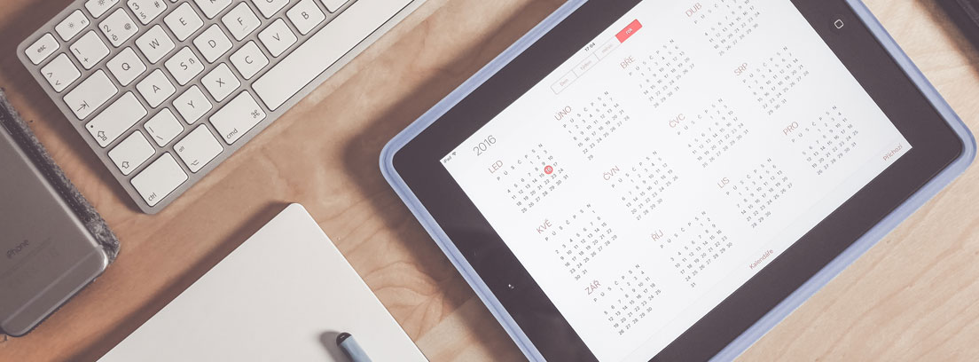 Vista cenital de una mesa con un teclado, un cuaderno y un calendario en el que apuntar los días de asuntos propios