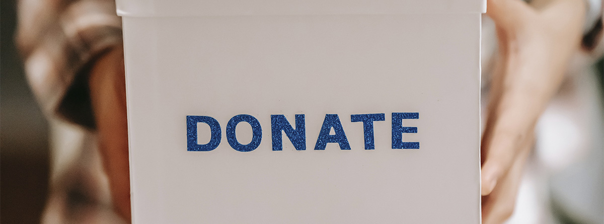 Manos sosteniendo una hucha de donativos
